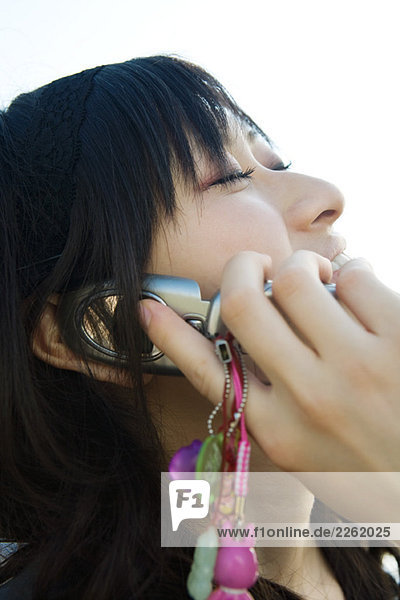 Young woman using cell phone  head back  eyes closed  close-up
