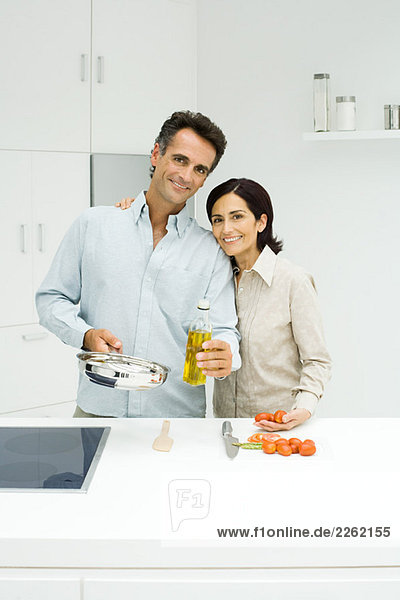 Couple cooking together in kitchen  both smiling at camera