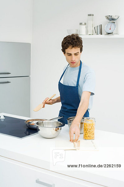 Junger Mann beim Kochen in der Küche  Rezept aus dem Buch lesen