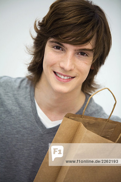 Junger Mann mit Einkaufstasche  lächelnd vor der Kamera  Porträt