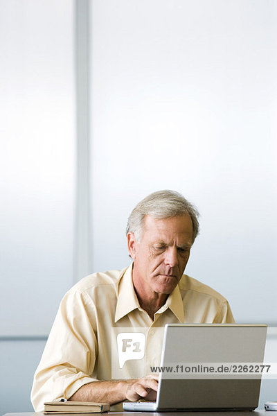 Man sitting  using laptop computer  looking down