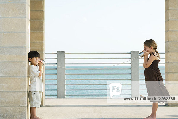 Zwei Kinder spielen mit Blechdosentelefon  Seitenansicht