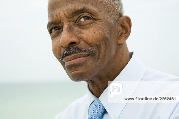 Älterer Mann schaut auf  lächelnd  abgeschnittenes Porträt
