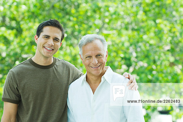Mature man and adult son smiling at camera together outdoors  portrait