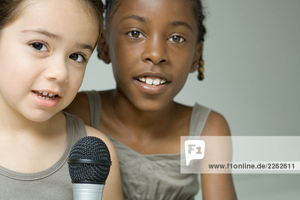 Zwei junge Mädchen singen zusammen ins Mikrofon  beide schauen in die Kamera.