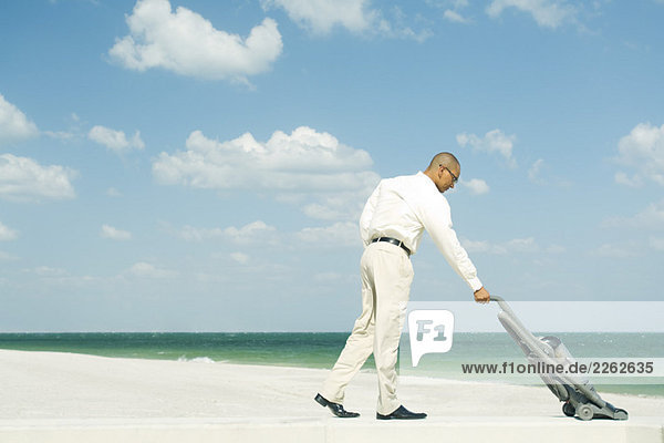 Man vacuuming beach  full length