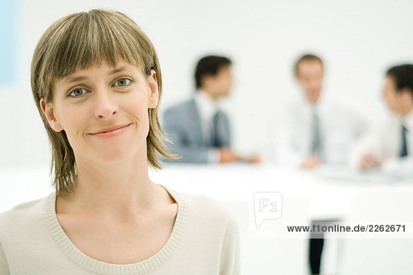 Geschäftsfrau lächelt Kamera  Portrait  Geschäftsleute im Hintergrund