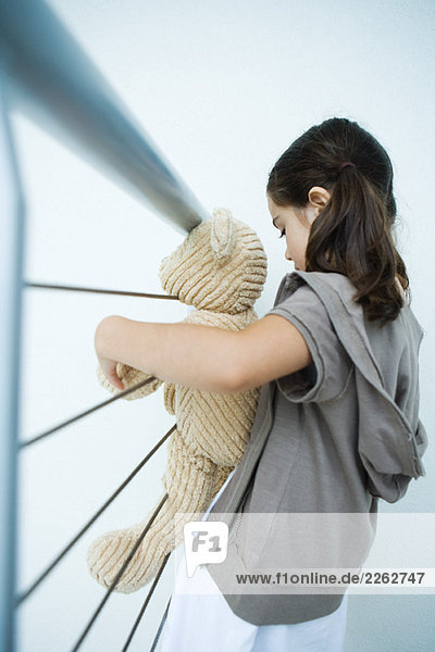 Kleines Mädchen mit Teddybär  an Geländer gelehnt  Seitenansicht