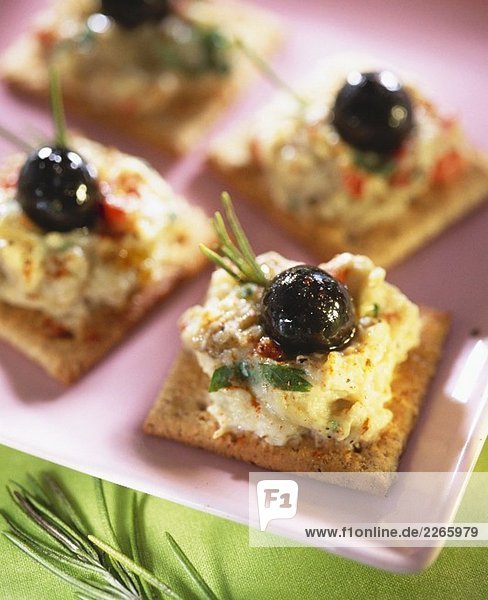 Crackers mit Auberginencreme und schwarzen Oliven