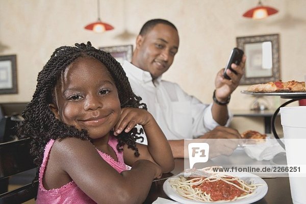 Father and daughter with pizza and pasta in restaurant