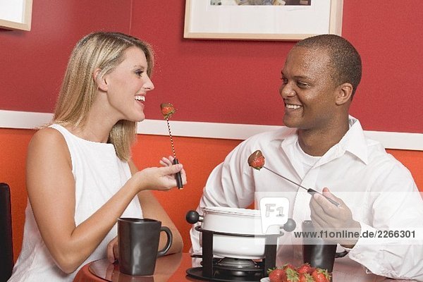 Junge Frau und Mann beim Schokofondue mit Erdbeeren