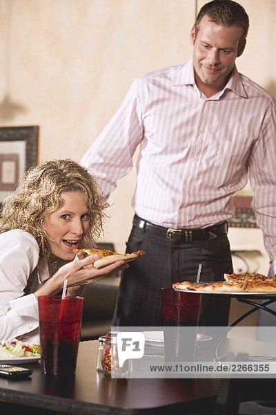 Woman in restaurant eating pizza  man just arriving