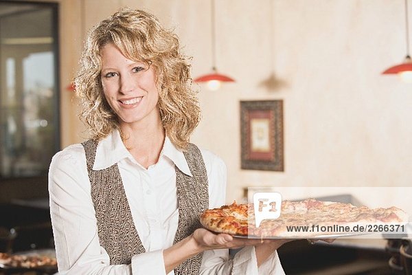 Blonde Frau hält eine Pizza