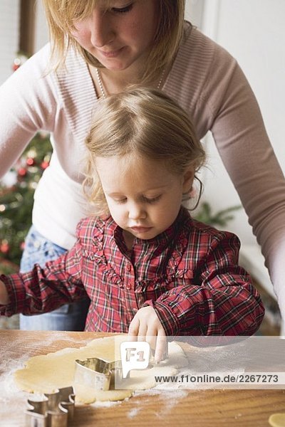 Mutter und Kind stechen Weihnachtsplätzchen aus