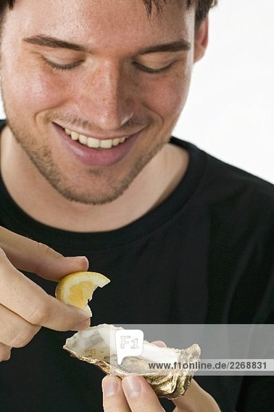 Man squeezing lemon juice on to a fresh oyster