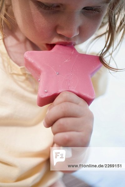 Kleines Mädchen isst rosa Eis am Stiel