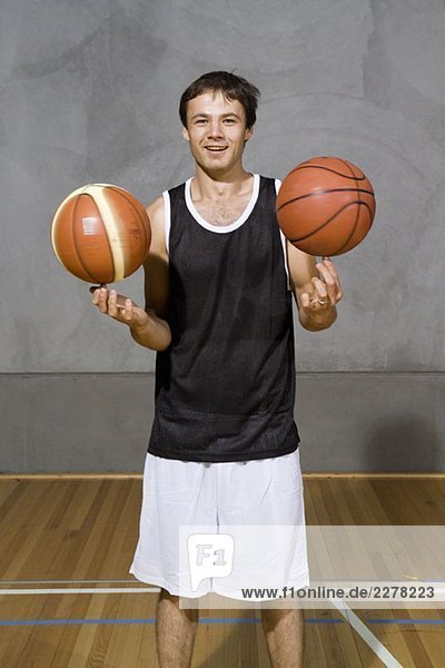 Ein junger Mann  der zwei Basketbälle an seinen Fingern dreht.