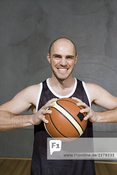 Ein junger Mann hält einen Basketball  der sich darauf vorbereitet  ihn zu werfen.