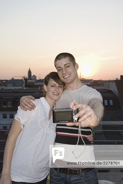 Ein junges Paar  das sich auf einer Dachterrasse fotografiert.