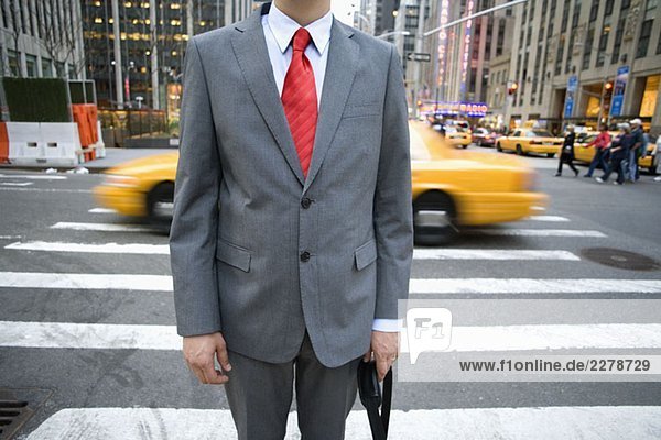 Midsection of a businessman standing in front of a pedestrian crossing