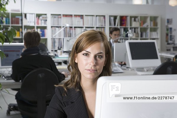 Eine Frau  die hinter einem Computer in einem Büro sitzt.