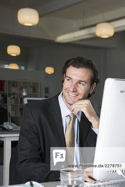 Ein Geschäftsmann  der an einem Computer in einem Büro sitzt.