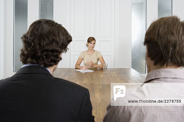 Eine Frau trifft sich mit zwei Männern in einem Sitzungssaal.