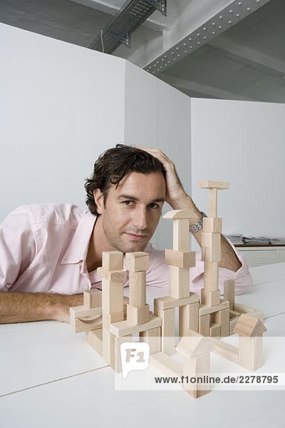 Ein Mann  der Holzbausteine am Schreibtisch benutzt.