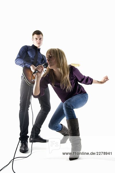 Studioaufnahme eines Mannes  der E-Gitarre spielt und einer Frau  die in ein Mikrofon singt.