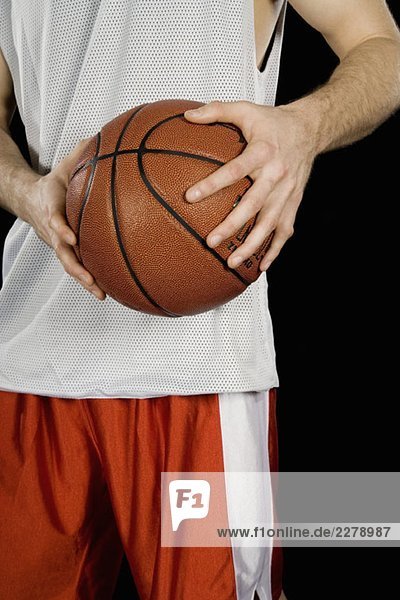 Ein Basketballspieler  der einen Basketball hält.