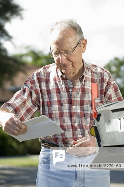 Ein älterer Mann  der den Briefkasten überprüft.