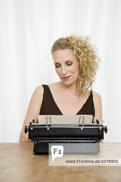Eine erwachsene Frau  die auf ein Dokument in einer altmodischen Schreibmaschine herabblickt.