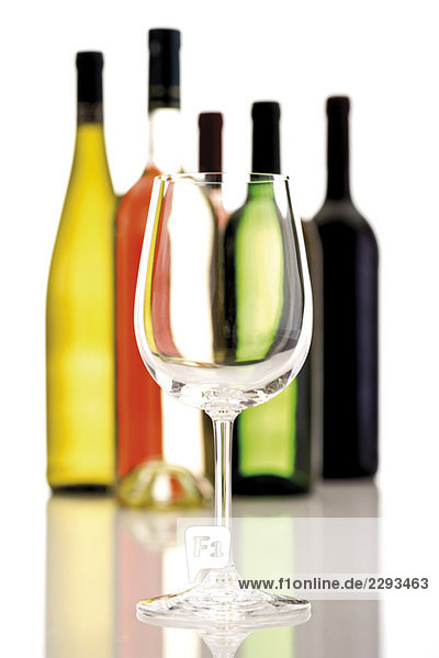 Weinglas vor Weinflaschen  Nahaufnahme