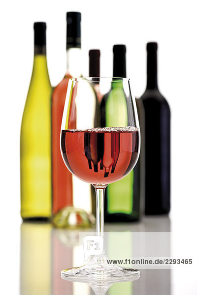 Ein Glas Rotwein  in Hintergrundweinflaschen  Nahaufnahme
