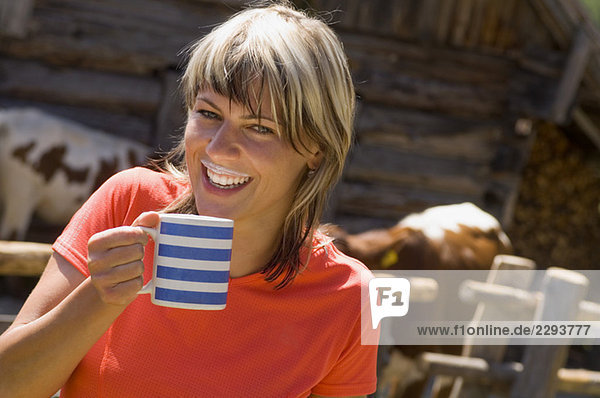 Österreich  Salzburger Land  Junge Frau trinkt eine Tasse Milch