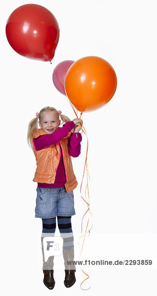 Girl (8-9) holding bunch of balloons  smiling  portrait