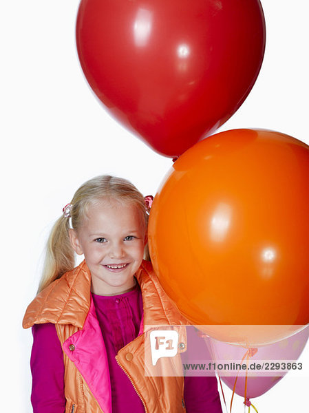 Girl (8-9) holding bunch of balloons  smiling  portrait
