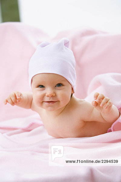 Mädchen (6-9 Monate) auf dem Bauch liegend  lächelnd