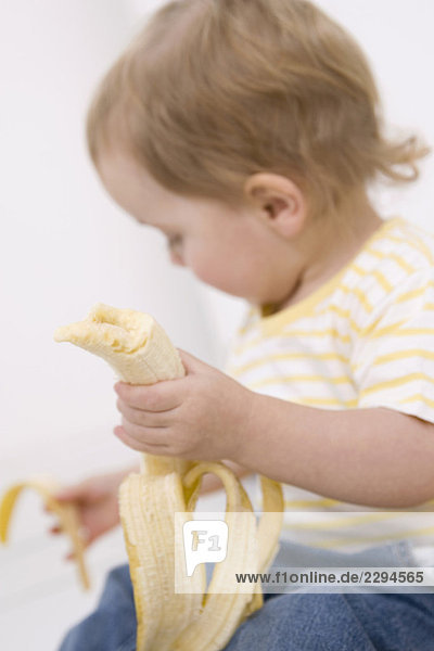 Baby Mädchen (2-3) beim Schälen einer Banane