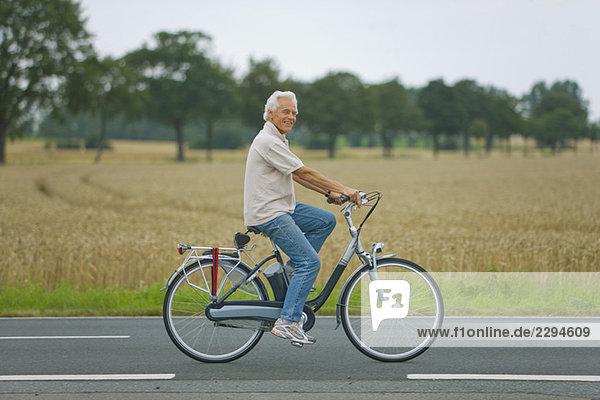 Senior man biking on road