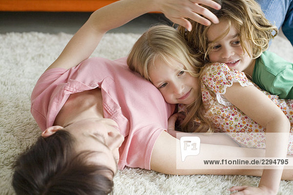 Mutter und Kinder liegen auf dem Boden im Wohnzimmer  Portrait