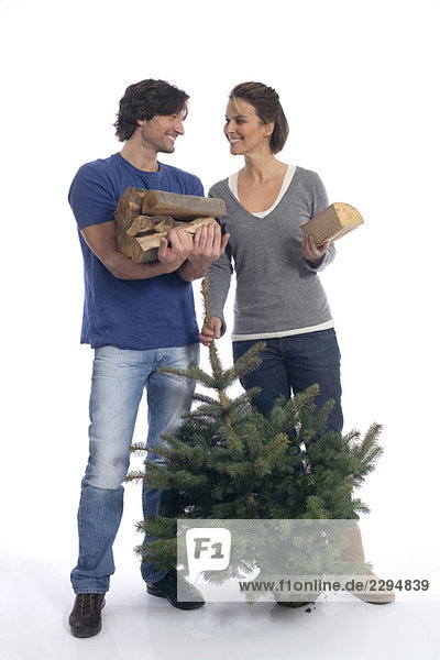 Paar mit Weihnachtsbaum und Brennholz
