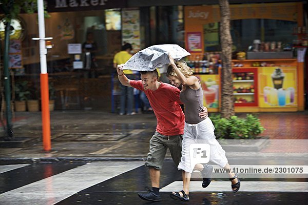 Ein skandinavischen Paar im Regen überqueren einer Straße Thailand