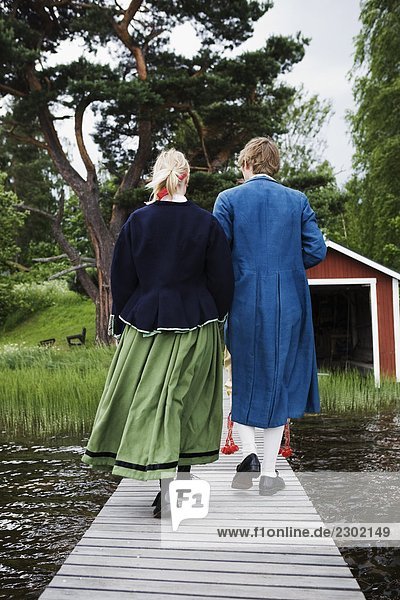 junges Paar tragen traditionelle Kostüme zu Fuß auf einen Steg Dalarna  Schweden