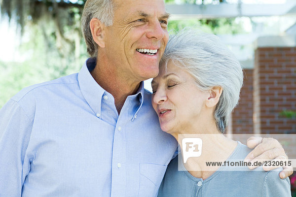 Mature couple embracing  woman's eyes closed  both smiling