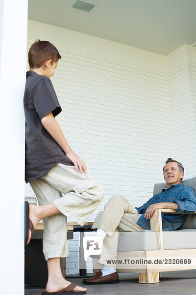 Großvater und Enkel von Angesicht zu Angesicht auf der Veranda  Mann sitzend  Junge stehend