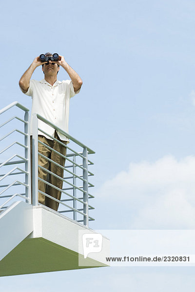 Man looking through binoculars  front view  low angle
