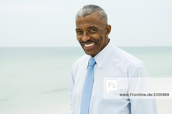 Businessman smiling at camera  sea in background