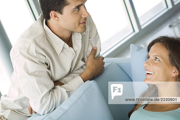 Young couple chatting together  female lying on couch  both smiling