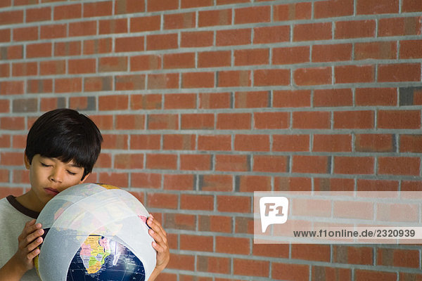 Junge hält den Globus in Bandagen gegen die Wange gewickelt  die Augen geschlossen.